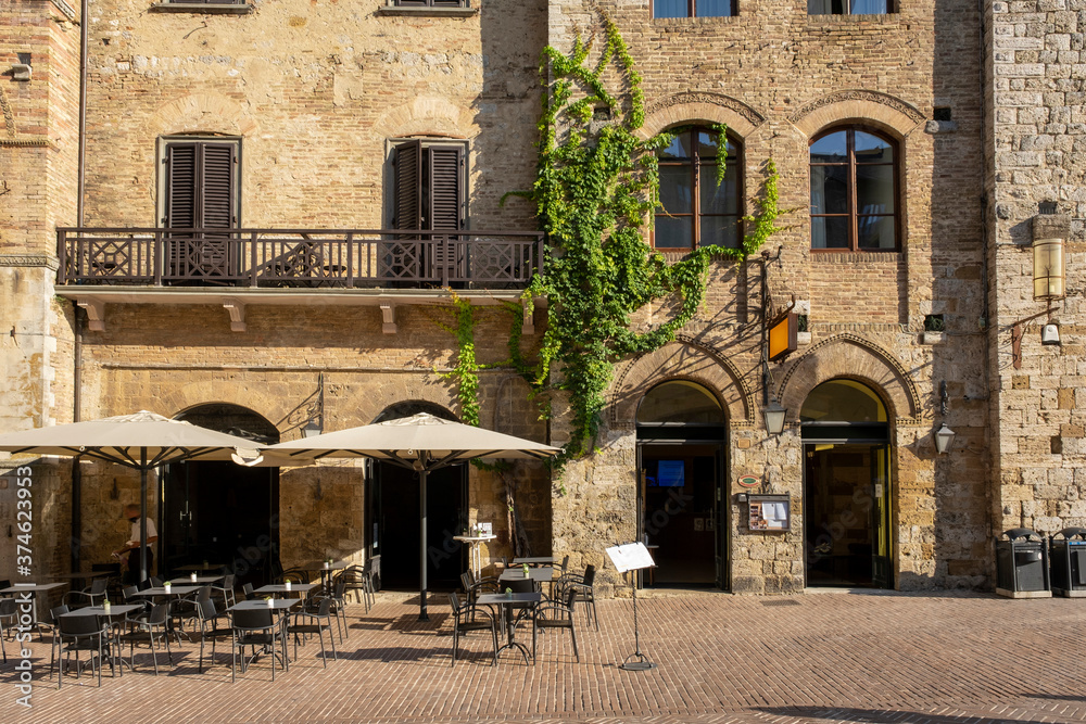 Cafe tables and chairs outside a stone building in Tuscany, Italy
