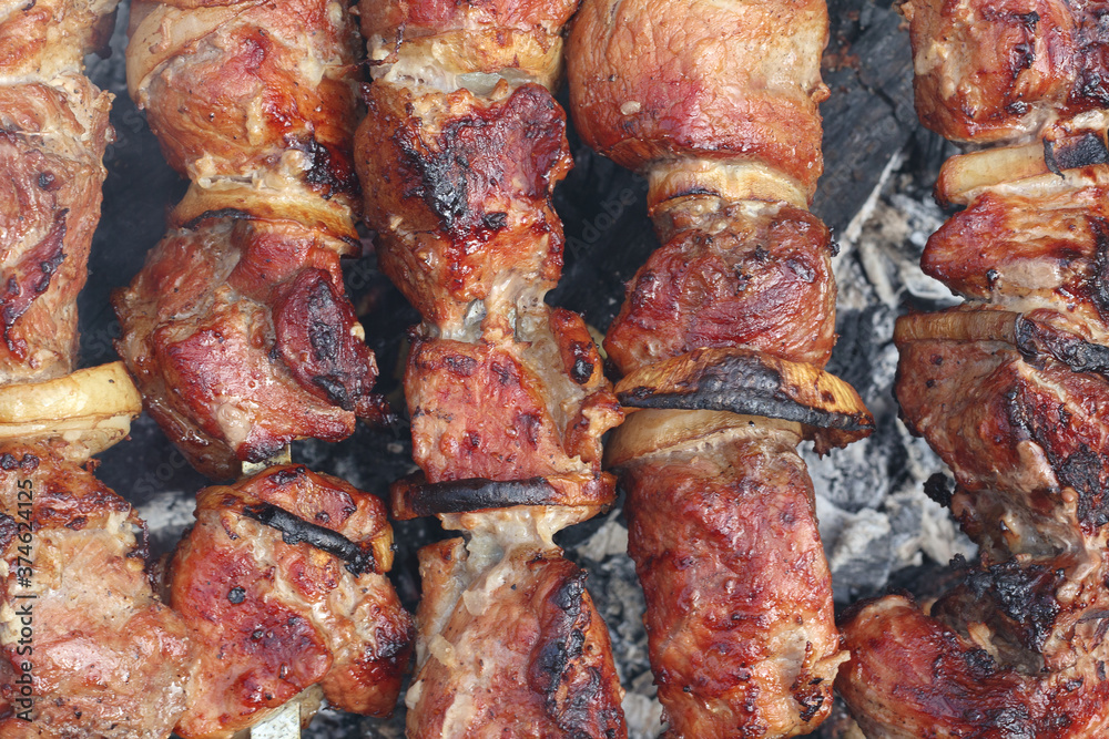 Tasty and juicy meat cooking on a skewer over an open fire outdoors, top view.