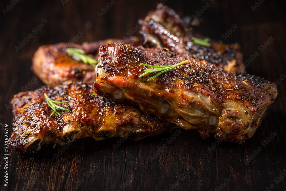 Grilled pork spare ribs with rosemary on wooden background.