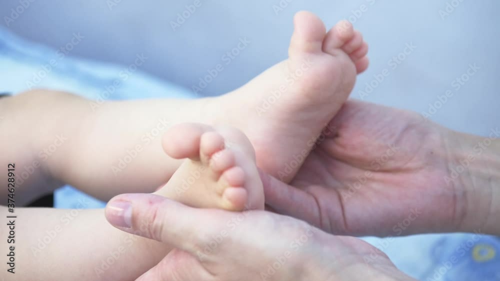Happy family. Mother's hands hold the baby's legs. The legs of a newborn baby are caressed by a mother. Happy family. Mother's hands hold the baby's legs. The legs of a newborn baby are caressed by a mother.