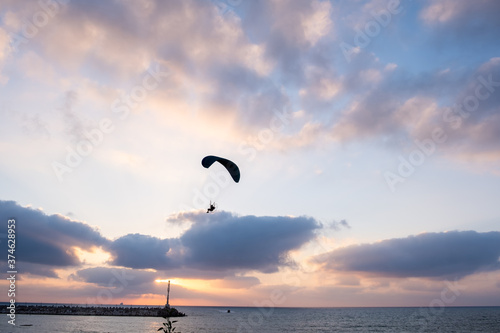 Motorized paraglider in amazing sunset sky above Ashkelon s Marina