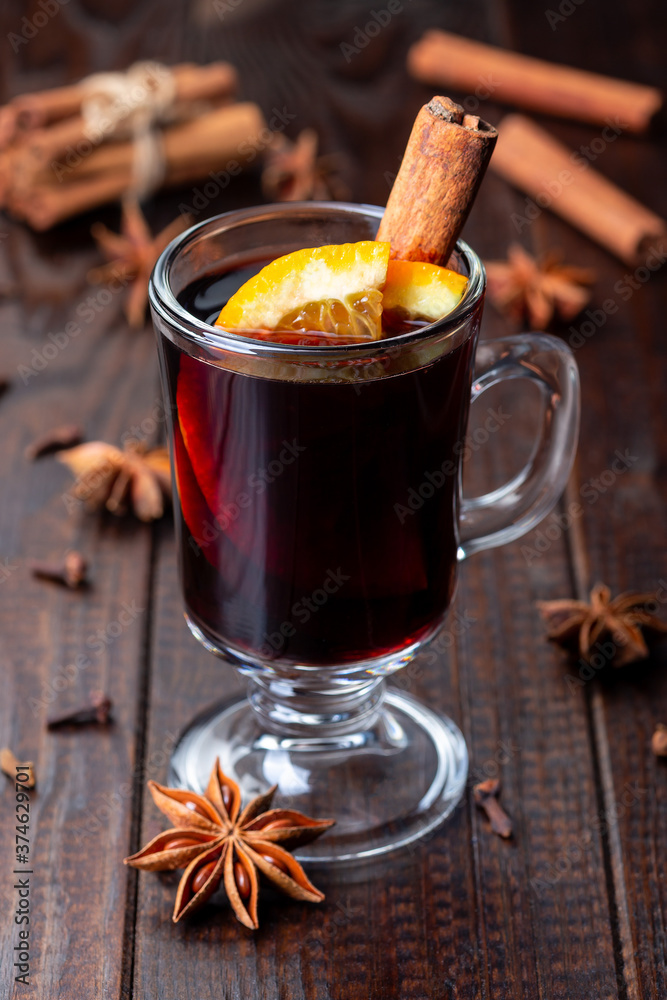 Glass of red glogg or mulled wine with orange slices and cinnamon stick on dark wooden background, vertical Glass of red glogg or mulled wine with orange slices and cinnamon stick on dark wooden background, vertical
