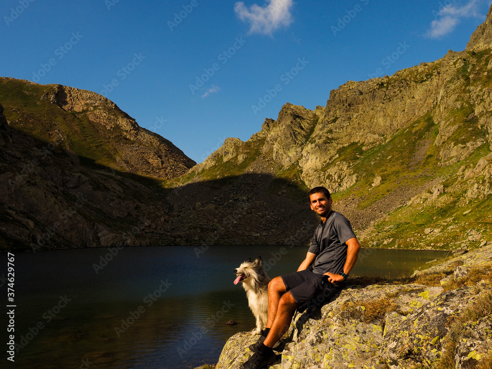 young man with his dog in a mountain lake