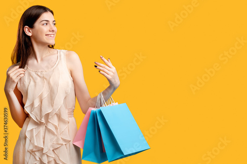 Easy shopping. Woman with shopper bags. Isolated on orange free space. Cyber monday. Sales and discounts