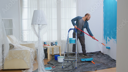 Bilde på lerret Young man painting wall with roller brush while renovating his apartment