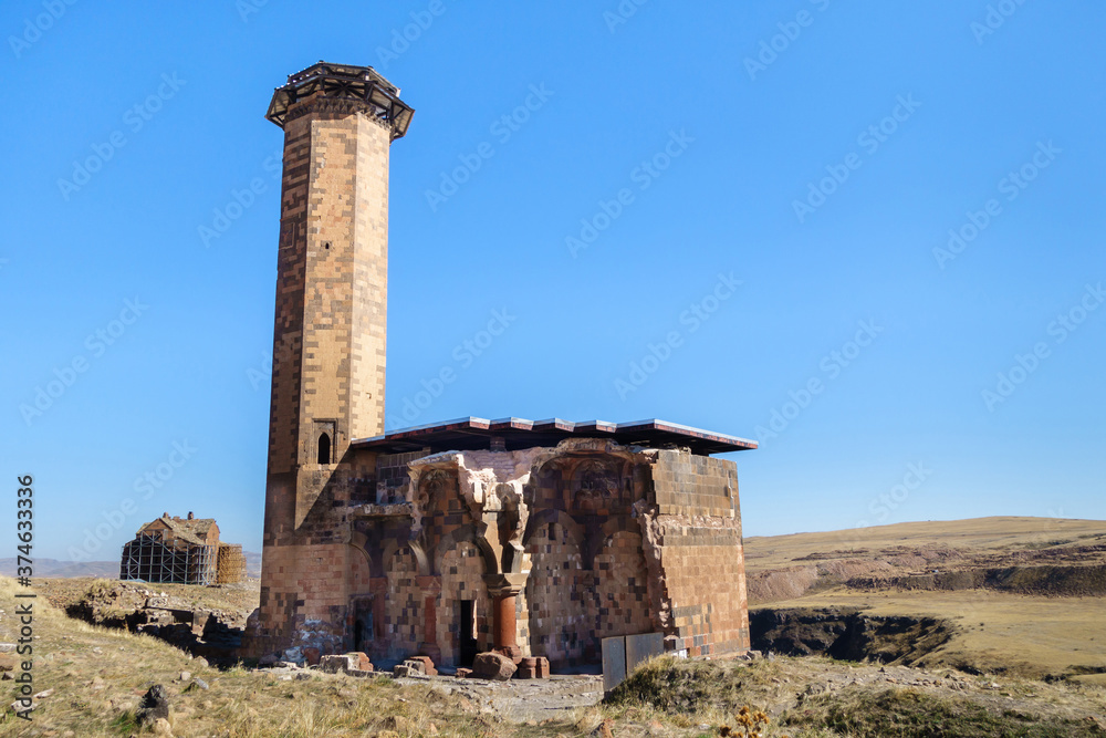 Seljuk mosque of Manuchihr & its minaret in medieval city Ani, near Kars, Turkey. It has untypical columns in construction. Cathedral of Ani is on background. All these buildings are UNESCO Objects