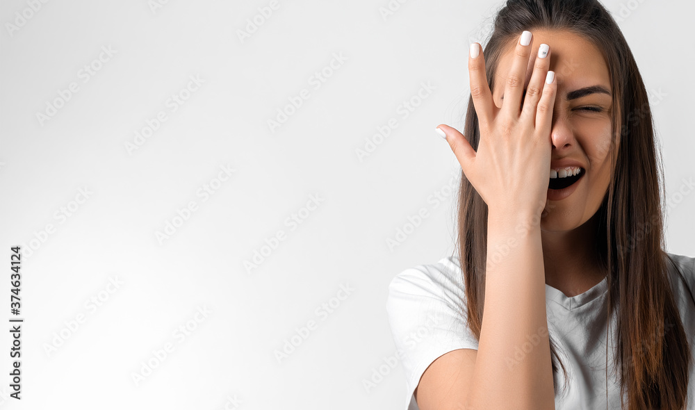 Shocked young woman with long chestnut hair covering face with hand. Keep silence concept. Copy space Shocked young woman with long chestnut hair covering face with hand. Keep silence concept. Copy space
