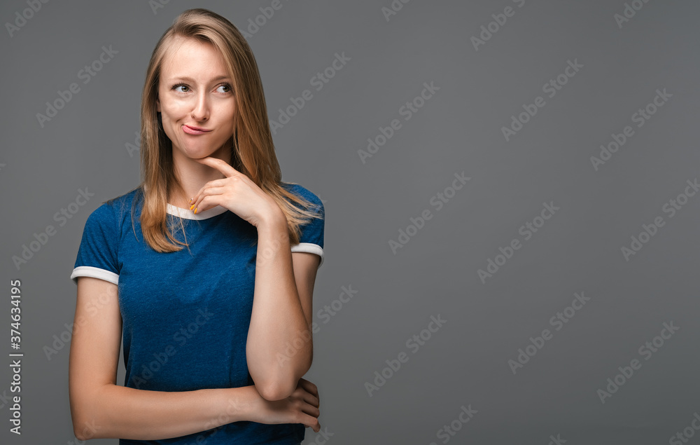 Thoughtful female is standing with hand raised on chin and looking thoughtfully away. Concept of thinking. Copy space Thoughtful female is standing with hand raised on chin and looking thoughtfully away. Concept of thinking. Copy space