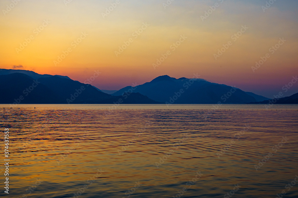 
pink orange sunrise over blue sea and mountains