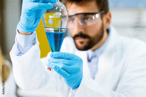 Researcher working with blue liquid at separatory funnel photo
