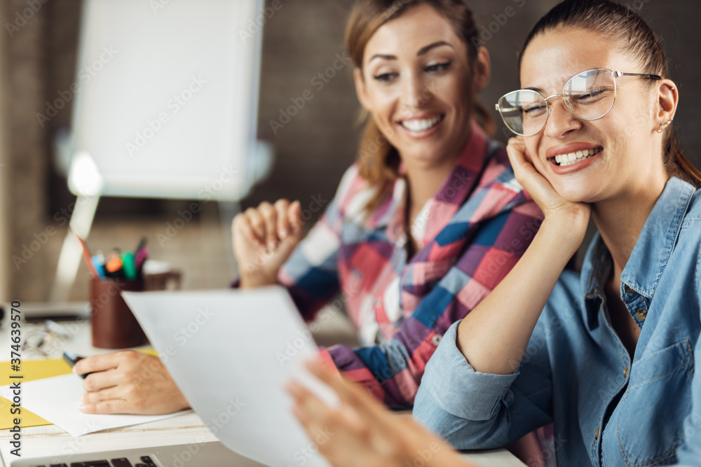 Young cheerful colleagues talking about reports while working at casual office Young cheerful colleagues talking about reports while working at casual office