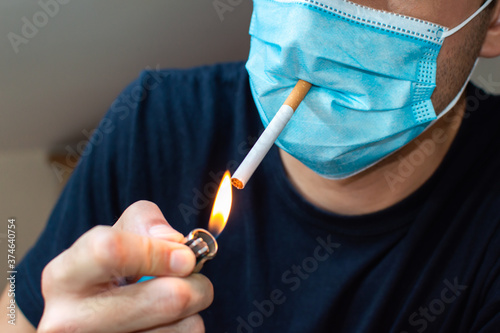 Young man with mask lighting a cigarette. Coronavirus funny concept