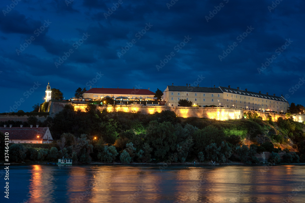 Petrovaradin fortress in Novi Sad, Serbia illuminated with colorful street lights and reflection in the Danube river water