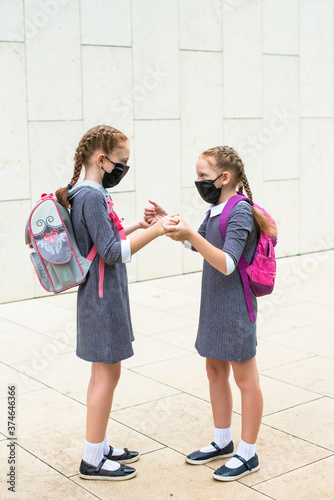 Two elementary school students in medical masks on the face. sisters with school bags. Back to school. first graders.