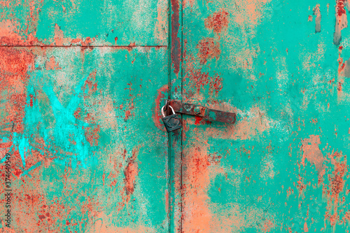 Old rusted grungy metal garage door with latch and padlock