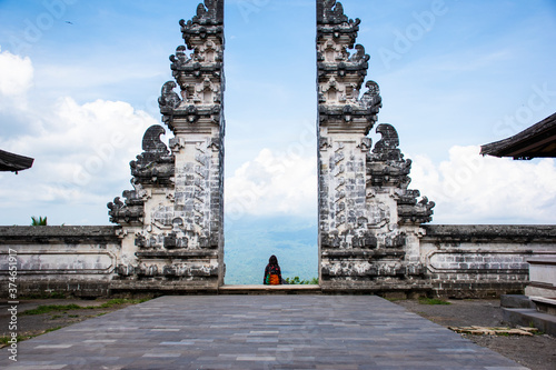 An European tourists taking pictures in Hindu temple heaven's gate wearing Sarong with blue background sky in Bali