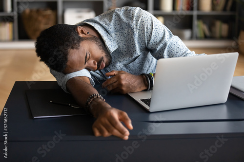 Фототапет Exhausted tired African American businessman entrepreneur lying on desk with clo