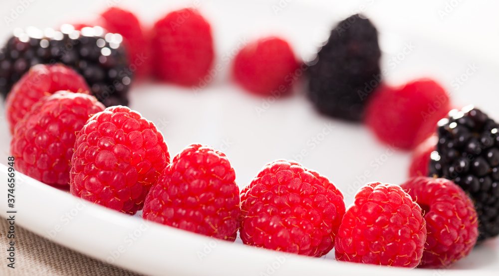 raspberries and blackberries laid out on a white plate in circle raspberries and blackberries laid out on a white plate in circle
