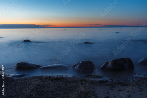 Sea shore and rocks at the sunset, cold blue sky. Nature composition.