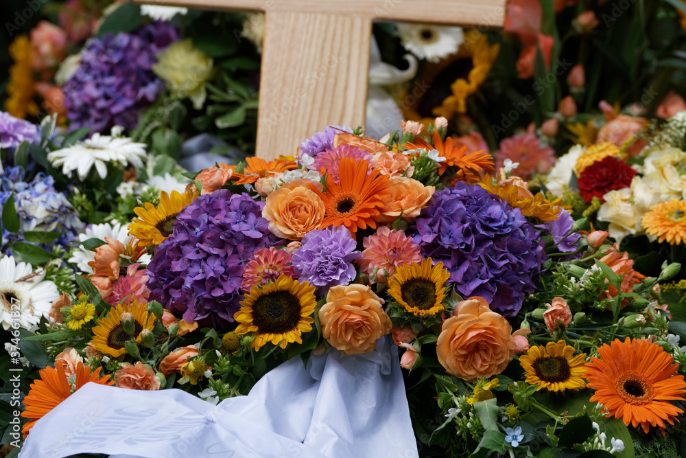 flowers and funeral wreaths on a new grave with wodden cross flowers and funeral wreaths on a new grave with wodden cross