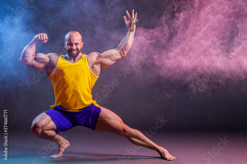 Powerful muscular man posing in the studio with red and blue smoke, Biceps and leg contraction