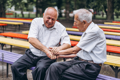 Two old senior adult men have a conversation outdoors in the city park. photo