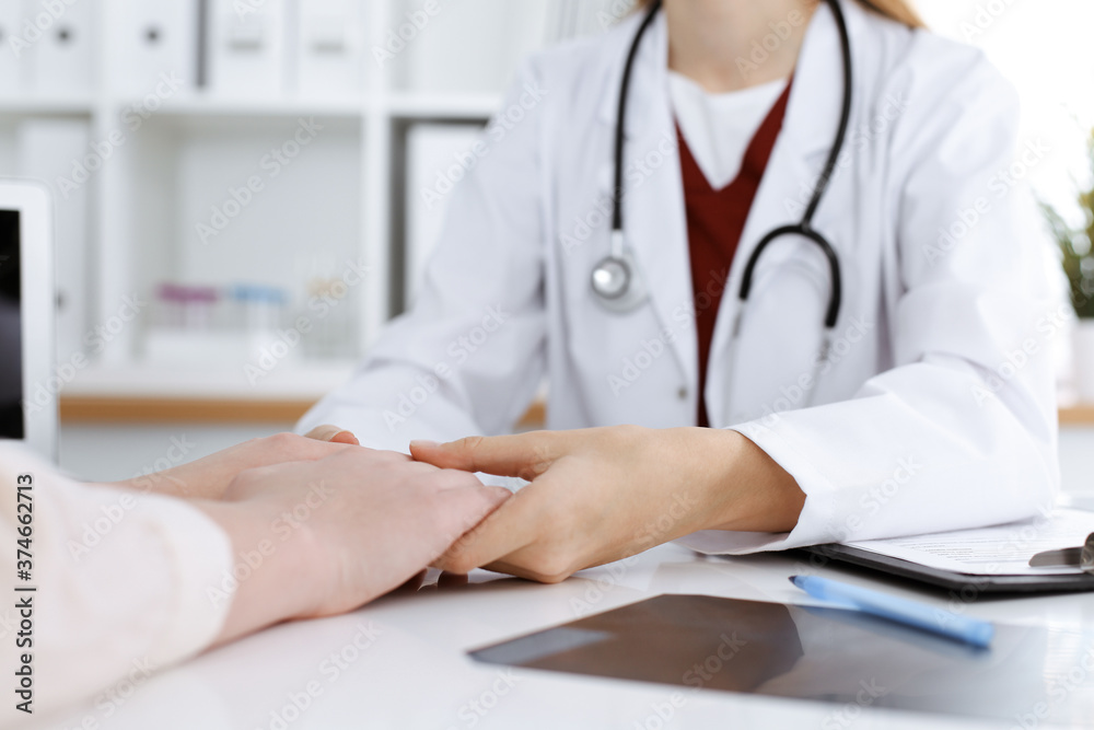 Hands of unknown woman-doctor reassuring her female patient, close-up. Medicine concept