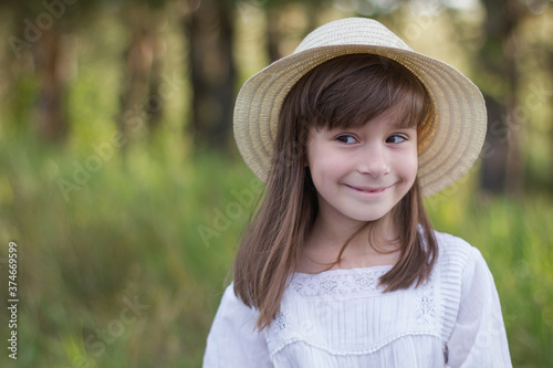 Cute smiling girl in a white dress stands near field