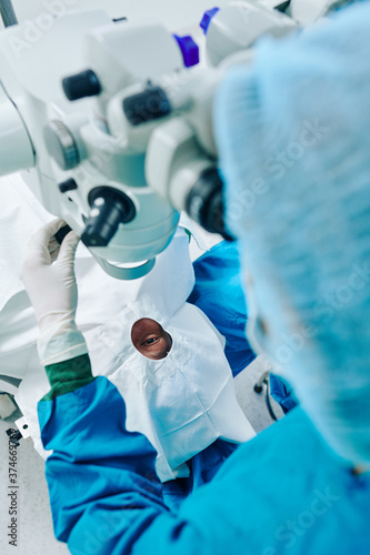 Surgeon operating eye of patient and using surgical microscope at the operating room