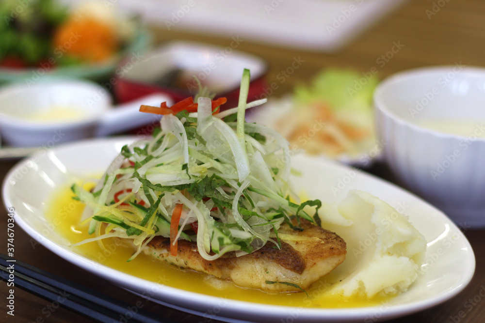 Close up of a set of delicious grilled fish served with vegetable salad topping and sweet sauce, Hiroshima, Japan, soft focus