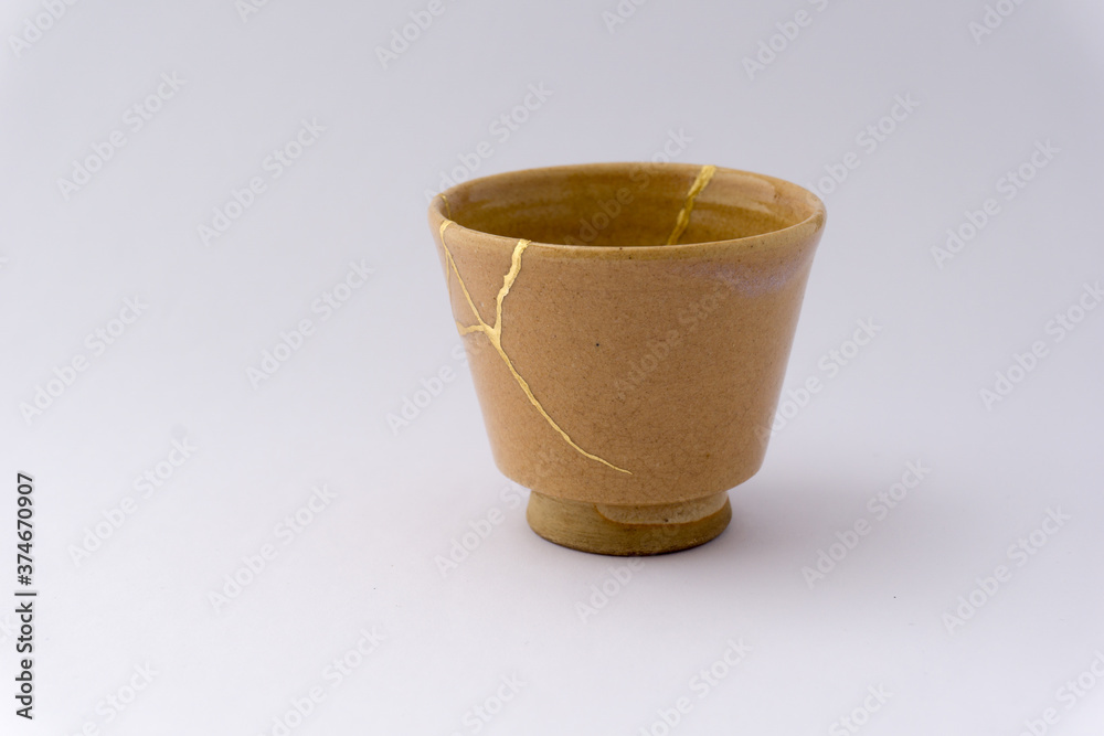 Kintsugi beige sake cup. Gold cracks restoration on old Japanese