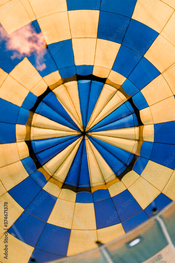 Naklejka premium Close up of inside of colourful blue-yellow hot air balloon. Air balloon, view of the flame inside of a hot air balloon being inflated