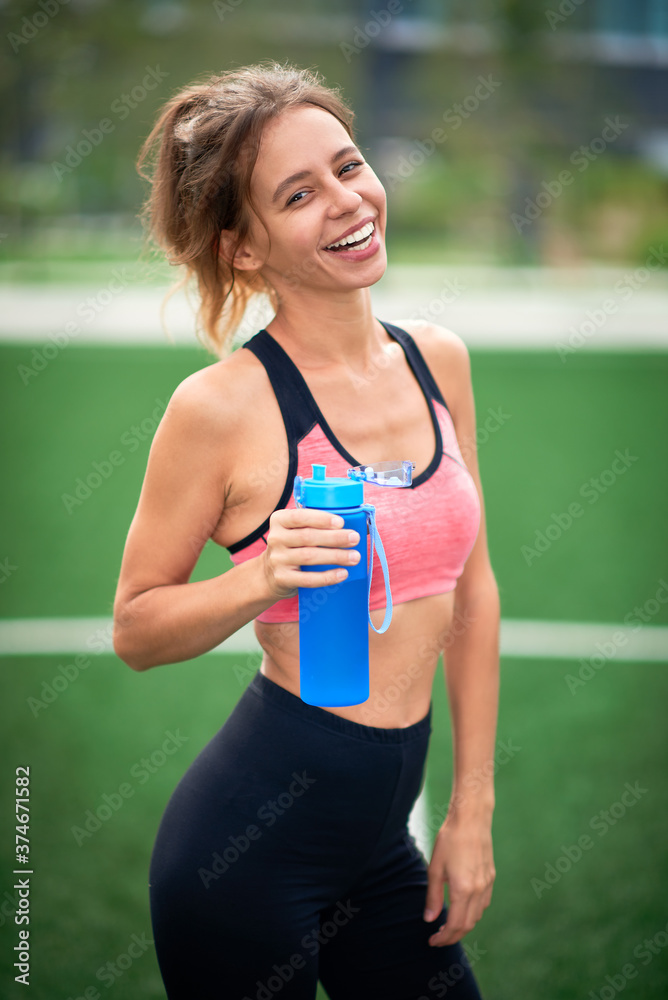 Sporty and happy girl with a bottle of water in her hands