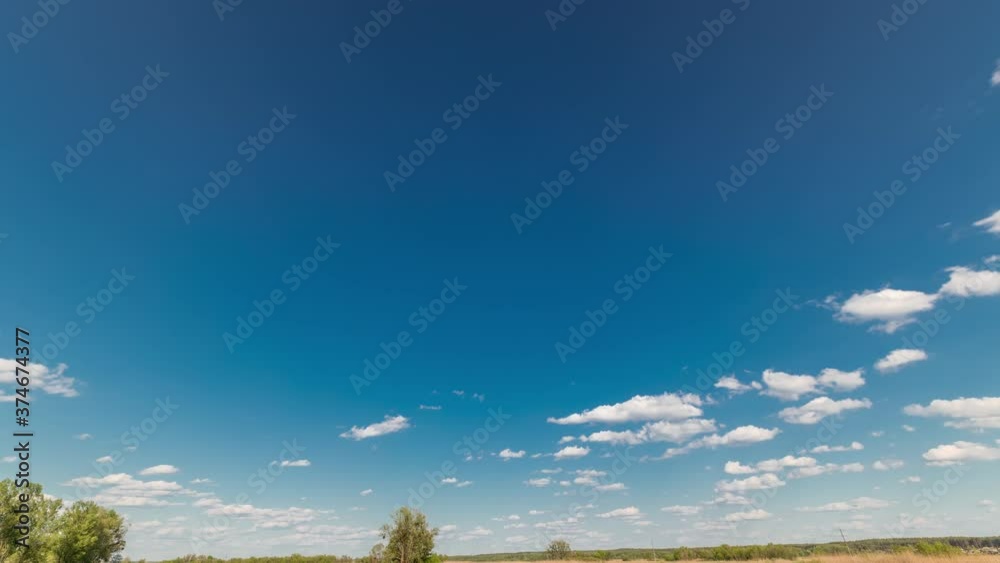 White clouds mooving on a blue sky over green field with grass and trees timelapse White clouds mooving on a blue sky over green field with grass and trees timelapse