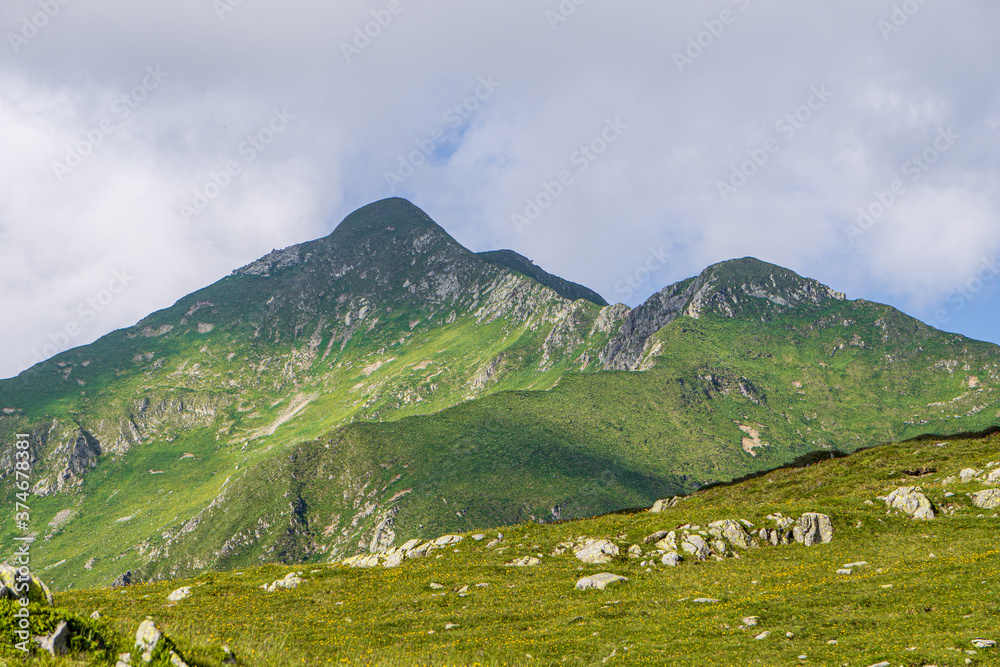 The meadows, the views and the peaks of the orobie alps during a summer afternoon, near the San Marco pass, Lombardy, Italy - June 2020