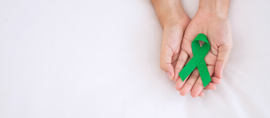 Man holding green Ribbon for supporting people living and illness. Liver, Gallbladders bile duct, kidney Cancer and Lymphoma Awareness month concept