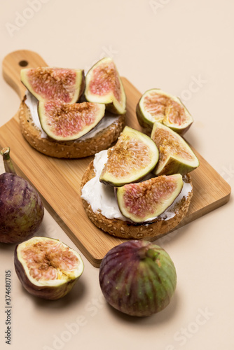 Canape or Crostini with Toasted Baguette Cream Cheese and Figs on Wooden Board Delicious Appetizer Lunch Yellow Background Vertical photo