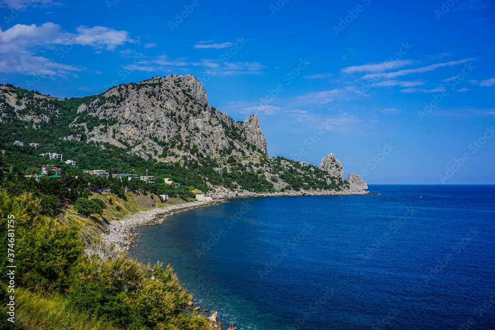 Rock covered with green vegetation hanging over the calm blue sea Rock covered with green vegetation hanging over the calm blue sea