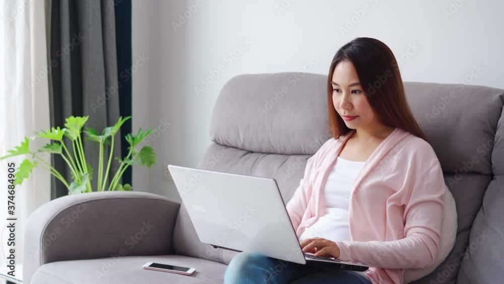 Young woman sitting at living room and working on laptop at home
Young woman sitting at living room and working on laptop at home