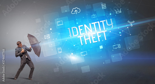 Businessman defending with umbrella from cyber attack and IDENTITY THEFT inscription  online security concept