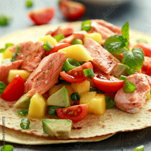 Salmon fish tacos with mango, avocado, tomato, spring onion and lime. Mexican food