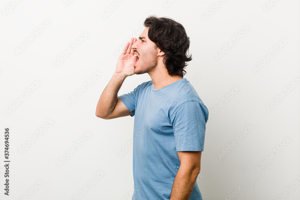 Young handsome man against a white background shouting and holding palm near opened mouth. Young handsome man against a white background shouting and holding palm near opened mouth.