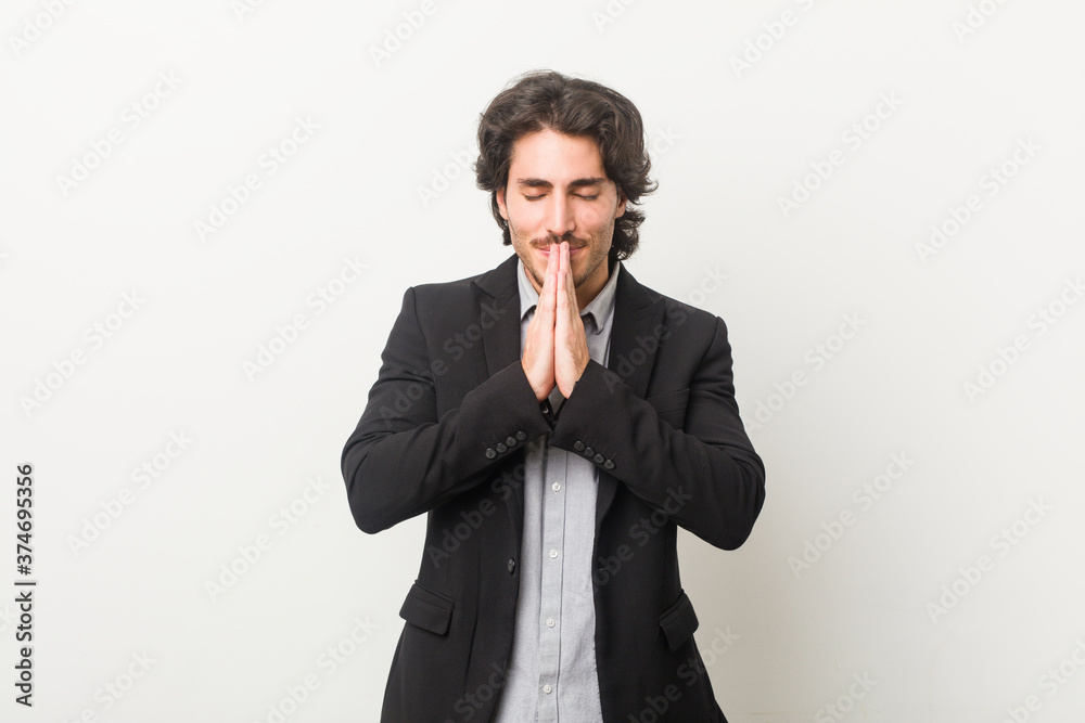 Young business man against a white background holding hands in pray near mouth, feels confident. Young business man against a white background holding hands in pray near mouth, feels confident.