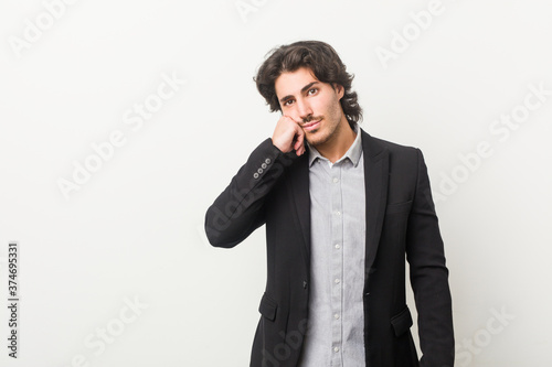 Young business man against a white background who feels sad and pensive, looking at copy space.