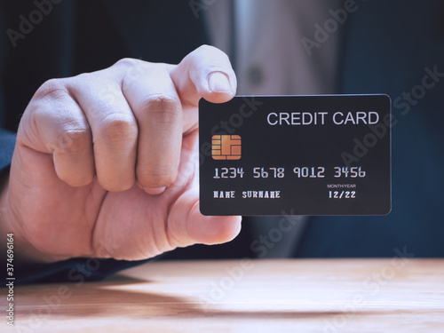 Businessman holding or showing black creadit card for shopping online. E-commerce, commercial, payment concept.
