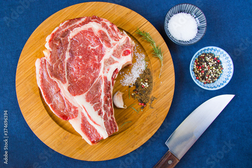 Raw beef meat on the table, spices and Rosemary, Rib eye steak ingredients. Pepper and coars salt. photo