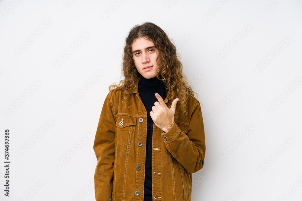 Long hair man posing isolated pointing with finger at you as if inviting come closer. Long hair man posing isolated pointing with finger at you as if inviting come closer.