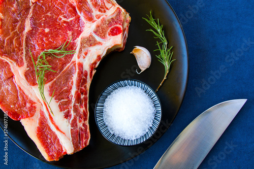 Raw beef meat on the table, spices and Rosemary, Rib eye steak ingredients. Pepper and coars salt. photo