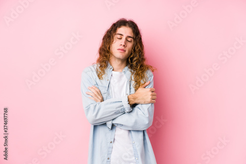 Long hair man posing isolated hugs, smiling carefree and happy.