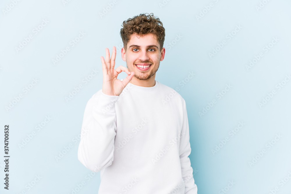 Young blond curly hair caucasian man isolated cheerful and confident showing ok gesture. Young blond curly hair caucasian man isolated cheerful and confident showing ok gesture.